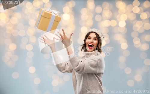 Image of young woman in winter hat catching gift box