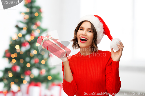 Image of happy young woman in santa hat with red gift box