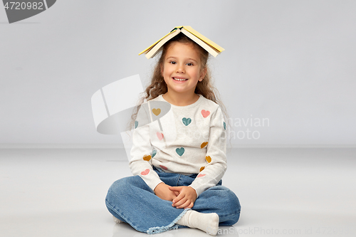 Image of portrait of smiling girl with book on head