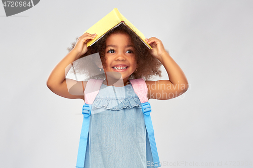 Image of happy little african girl with book and backpack