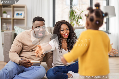 Image of african family playing with baby daughter at home