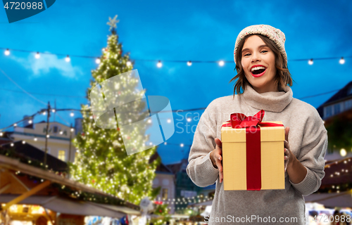 Image of woman in hat holding gift box at christmas market