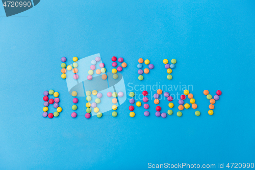 Image of happy birthday of candy drops on blue background