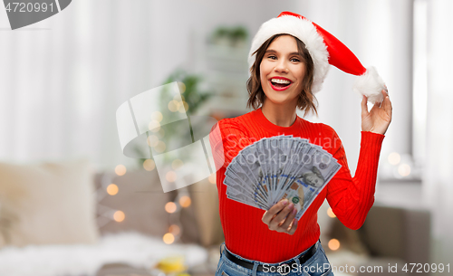 Image of happy woman in santa hat with money on christmas