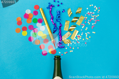 Image of champagne bottle with birthday party props on blue