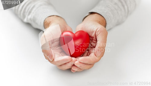 Image of close up of senior man holding red heart in hands