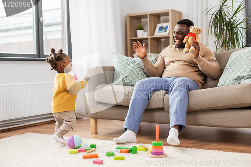 Image of african american father playing with baby at home