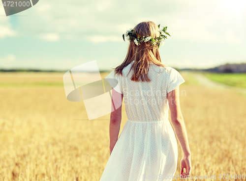 Image of happy young woman in flower wreath on cereal field