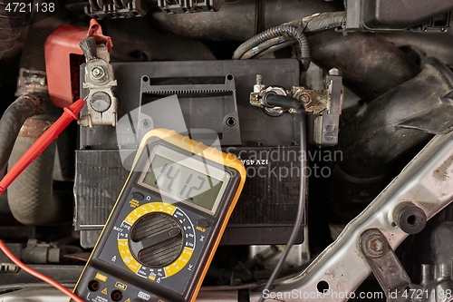 Image of Checking car battery and alternator voltage with running engine