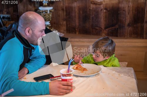 Image of father his little son eating a pizza