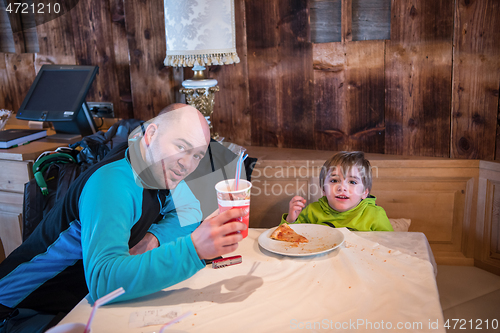 Image of father his little son eating a pizza
