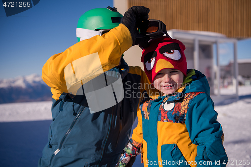 Image of father preparing his little son for the first time on a snowboar