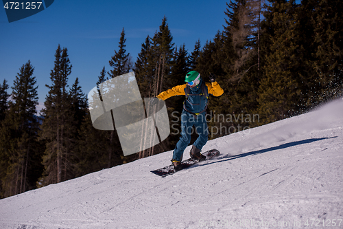 Image of snowboarder running down the slope and ride free style