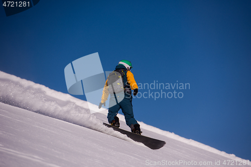 Image of snowboarder running down the slope and ride free style