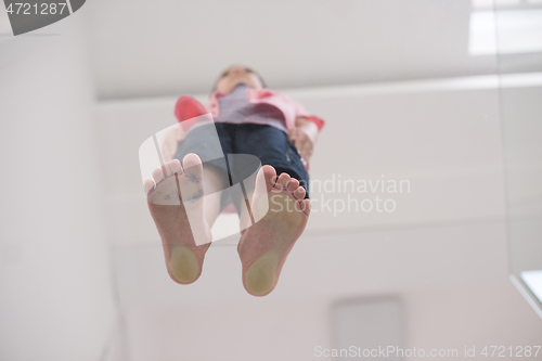 Image of little boy standing on transparent glass floor