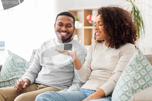 Image of african american couple with smart speaker at home