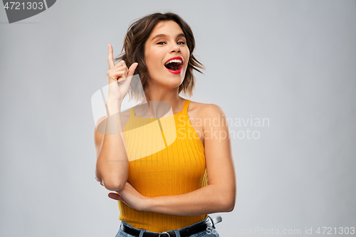 Image of happy smiling young woman pointing finger up