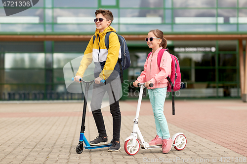 Image of happy school children with backpacks and scooters