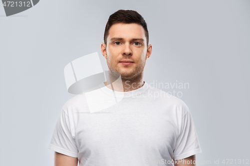 Image of portrait of serious young man in white t-shirt