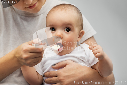 Image of close up of mother with spoon feeding little baby