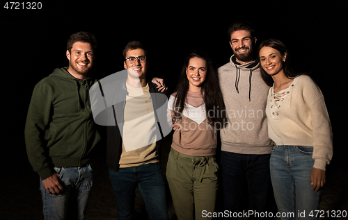 Image of group of happy smiling friends outdoors at night