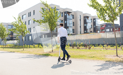 Image of young businessman riding electric scooter outdoors