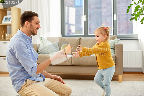 Image of father and baby daughter playing with ball at home