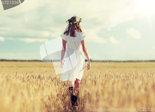 Image of happy young woman in flower wreath on cereal field