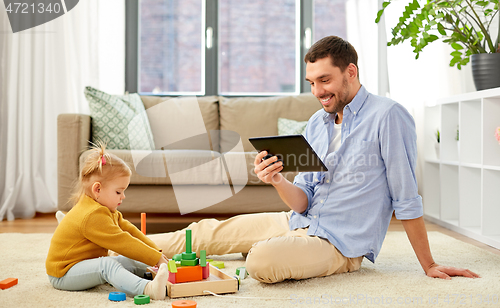 Image of father with tablet pc and baby daughter at home