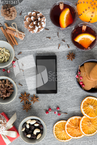 Image of smartphone, hot mulled wine and christmas spices