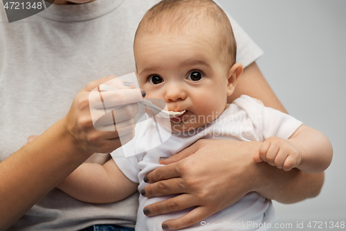 Image of close up of mother with spoon feeding little baby