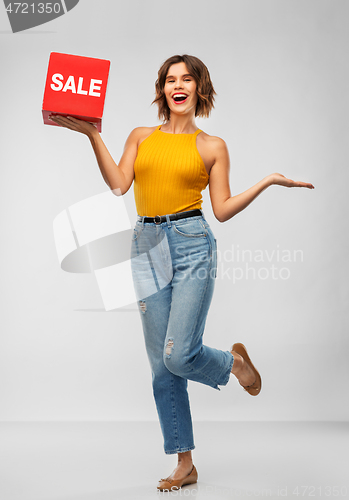 Image of happy smiling young woman posing with sale sign