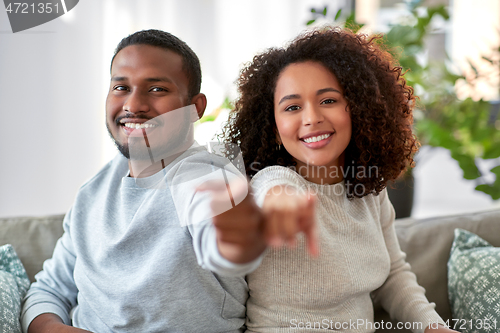 Image of happy african american couple pointing to camera