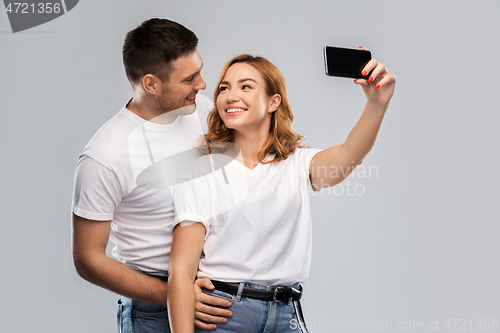 Image of happy couple in white t-shirts taking selfie