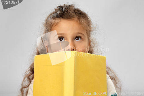 Image of little girl hiding behind yellow book