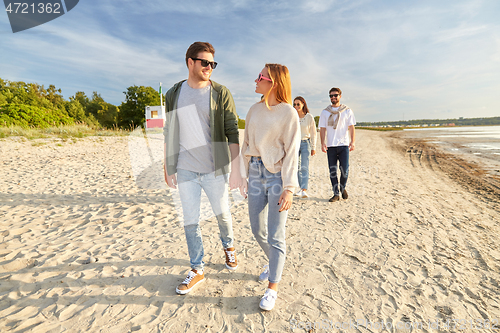 Image of happy friends walking along summer beach