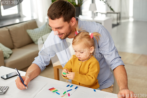 Image of working father with baby daughter at home office