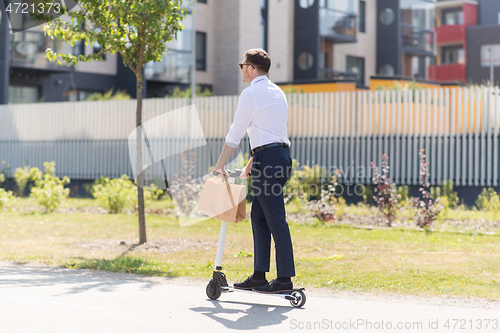 Image of businessman with takeaway paper bag riding scooter