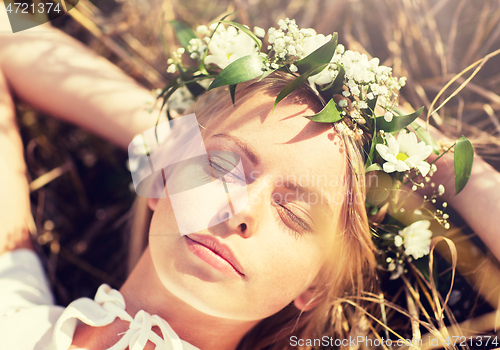 Image of happy woman in wreath of flowers lying on straw