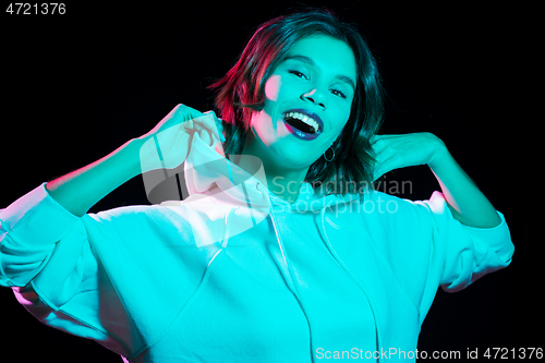 Image of woman wearing hoodie in neon lights over black