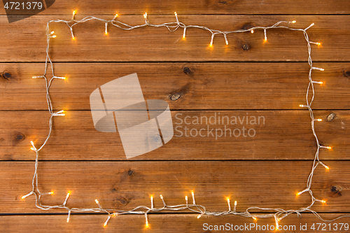 Image of frame of garland lights on wooden background