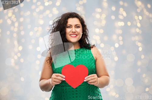 Image of happy woman holding red heart over lights