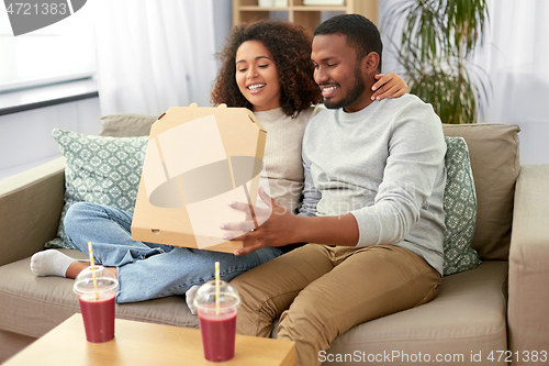 Image of happy african american couple eating pizza at home