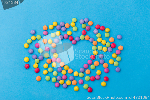 Image of candy drops in shape of heart on blue background