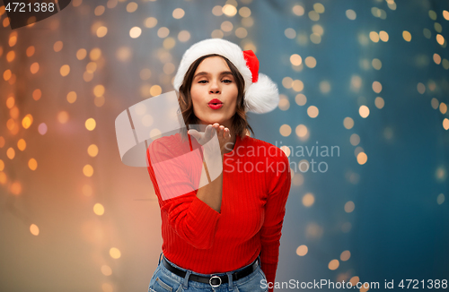 Image of woman in santa hat sending air kiss on christmas