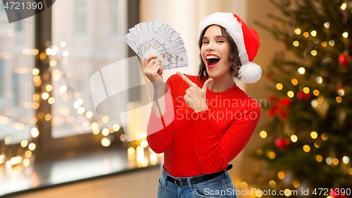 Image of happy woman in santa hat with money on christmas