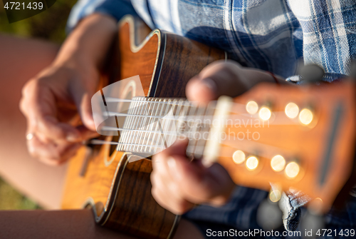 Image of Woman at sunset playing the ukulele