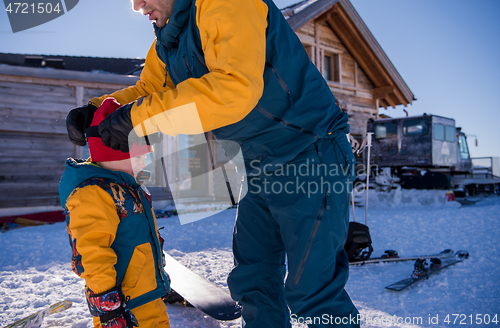 Image of father preparing his little son for the first time on a snowboar