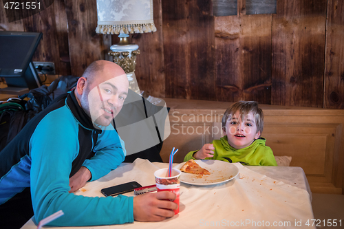 Image of father his little son eating a pizza