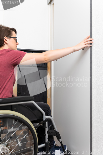 Image of disabled woman opens a door in her flat